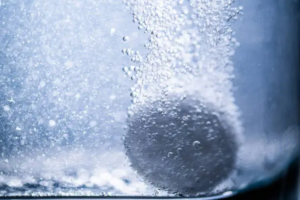 Photo of effervescent tablet in a glass of water.