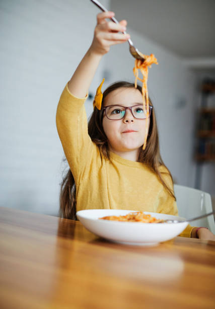 子供の娘の��女の子幸せなスパゲッティパスタ食べ物の食事の昼食の子供の頃 - child eating pasta spaghetti ストックフォトと画像