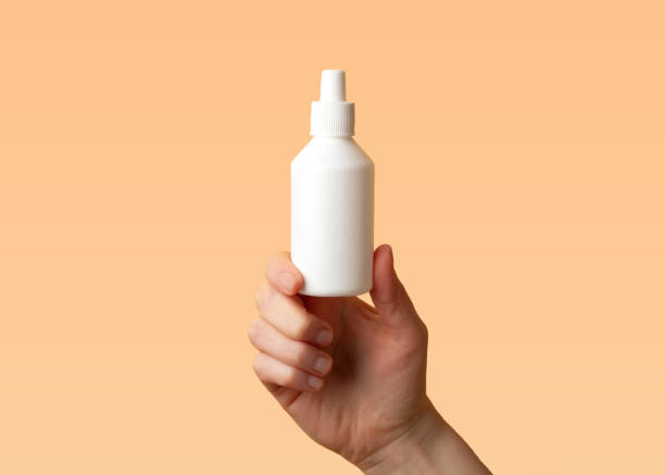 Viral disease prevention concept. Female hand holds a plastic bottle with a non-iodized antiseptic Chlorhexidine (chloroxylenol) on orange background. Coronavirus prevention. Safety rules during quarantine. Copy space for text Viral disease prevention concept. Female hand holds a plastic bottle with antiseptic chloroxylenol on orange background. Coronavirus prevention. Safety rules during quarantine. Copy space for text hydrogen peroxide stock pictures, royalty-free photos & images