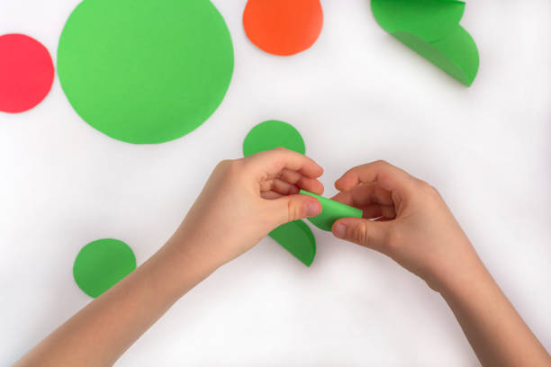 istock Concept of DIY and children's creativity. Step by step instruction: how to make applique frog from paper. Step 3 bending paper circle by child fingers. Creative activities with child during quarantine 1250622827