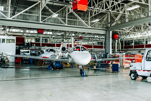 Two private jets parked in a service hangar at an airport.