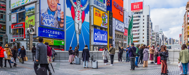 Tourists taking selfies in front of the iconic Glico running man neon sign in the crowded Dotonbori district of central Osaka, Japan’s vibrant second city.