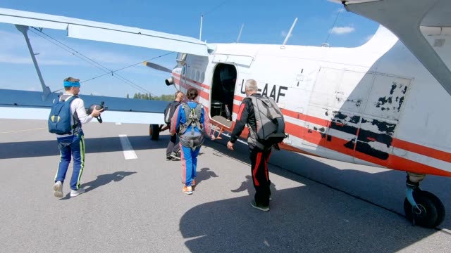 Skydivers board a plane on the runway of the airfield.