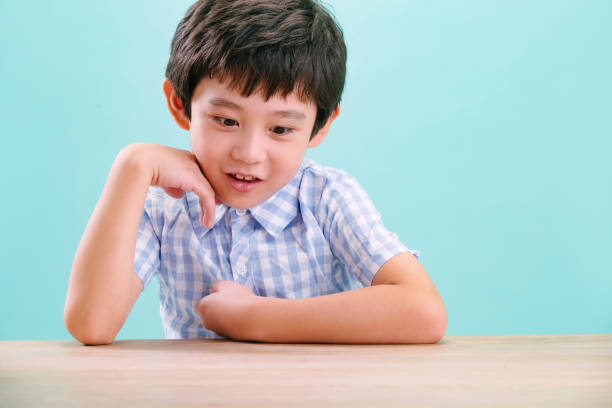 The little boy hand supporting his chin on his desk
