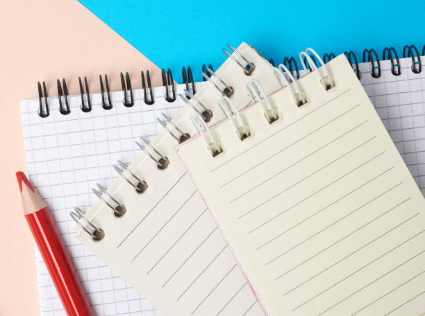 istock red wooden pencil and stack of spiral open notebooks with blank white sheets 1250628302