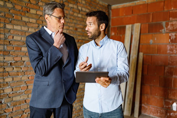 istock Mid adult businessmen working on touchpad at construction site. 1250628330