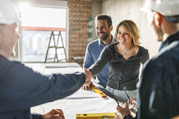 happy couple closed a deal with manual workers at construction site. - home remodeling imagens e fotografias de stock