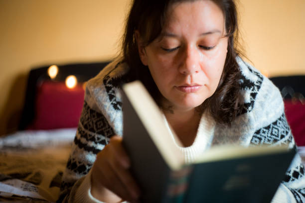 istock Woman reading book in cosy home environment 1250629728