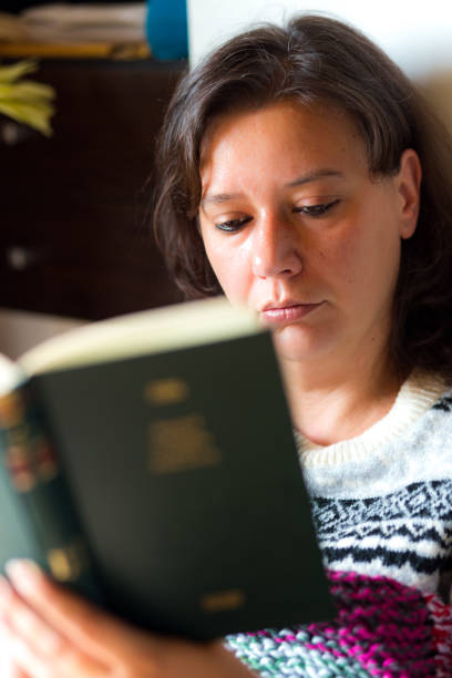 istock Woman reading book in cosy home environment 1250629836