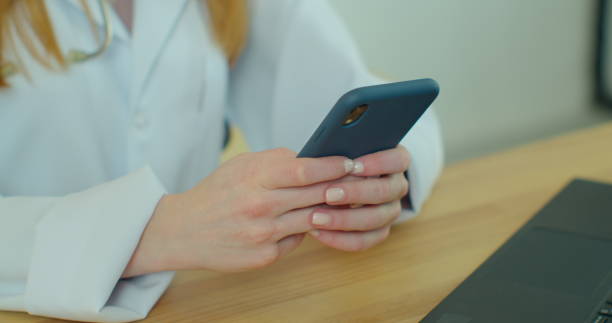 istock Female doctor in white coat using modern smartphone device with touch screen. Doctor using mobile phone texting to patient informing about medical test results. 1250631124