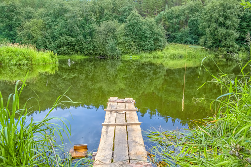 Fishing spot with wooden gangway on the river on a summer day