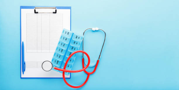istock Doctor appointment. Stethoscope, pill box, medical documents on doctors workplace in clinic long blue banner. Concept medicine health care, research, science.Coronovirus Covid-19 test analysis form 1250637561
