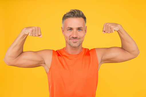 Train hard be strong. Strong man flex arms yellow background. Building strong biceps and triceps. Happy athlete show physical strength. Strong muscle workout. Sport and fitness. Beast mode.