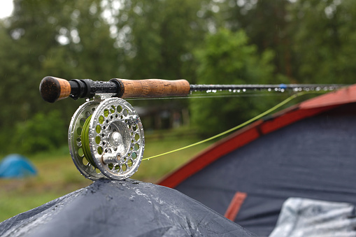 Close up view of fly fishing tackle. Fishing sport. Outgoing outdoor activities with tents. Tourism, fishing, active leisure. Hobby, resting time.