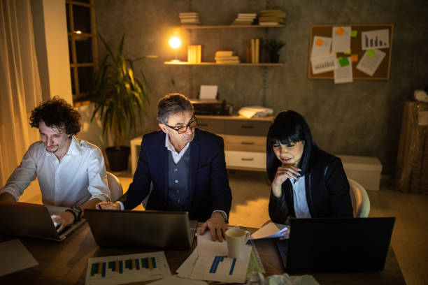 istock Coworkers looking at charts on papers while working late at night in office 1250641778