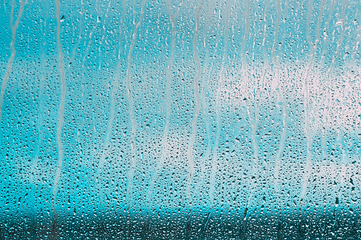 Drops Of Water Or Rain On Wet Glass Background. Moody Photo In Cold Blue Color.