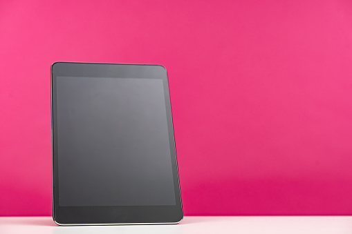 Digital tablet with empty screen on pink background. The scene is situated in controlled studio environment in front of orange background. Photo is taken with SONY AIII camera