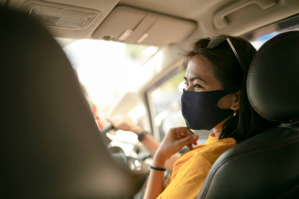 istock Woman with mask driving car 1250649462