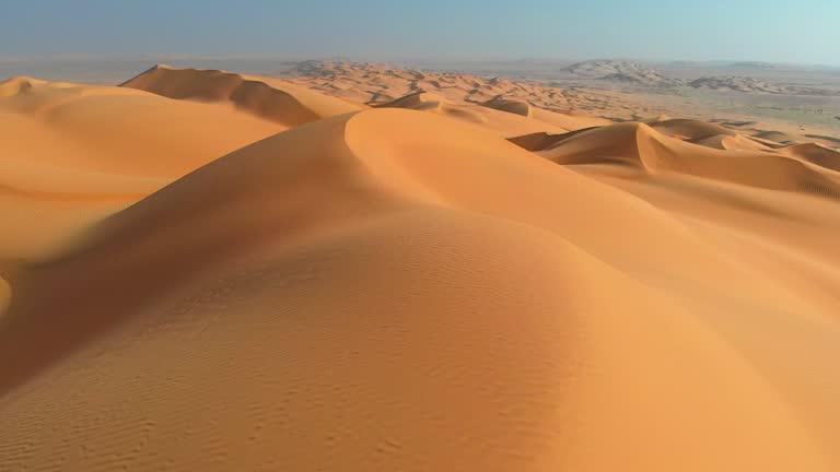 Rub' al Khali, aka Empty Quarter desert, Arabian Peninsula. Flying over curve shaped sand dunes during hot summer weather. Aerial shot, 4K