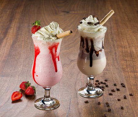 Cold coffee drink frappe (frappuccino), and milkshake with whipped cream and strawberry and caramel syrup,