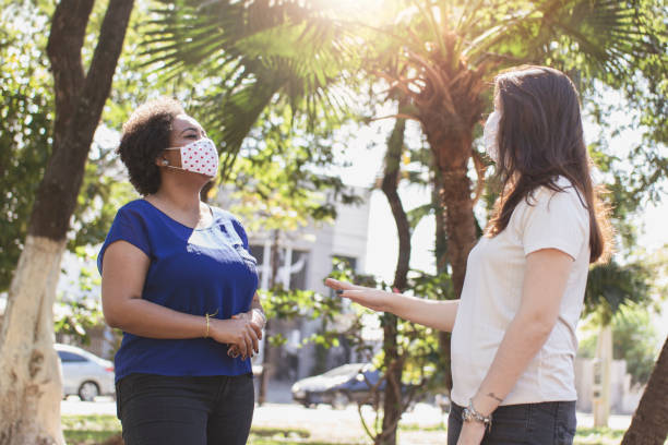 istock Two young women talking and wearing protective face mask. 1250666238