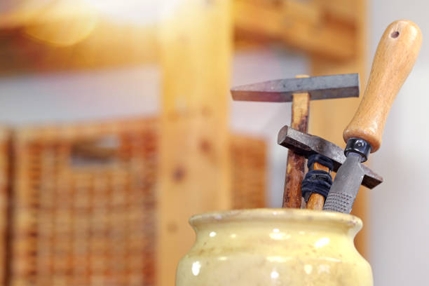 tools placed on a wooden workbench in a carpentry workshop with shelves and a ray of sunshine
