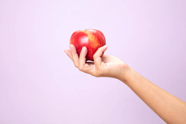 istock Hand Holding Red Apple on pink paper background. 1250670370