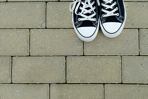 Teenager with black sneakers standing on the pavement, top view
