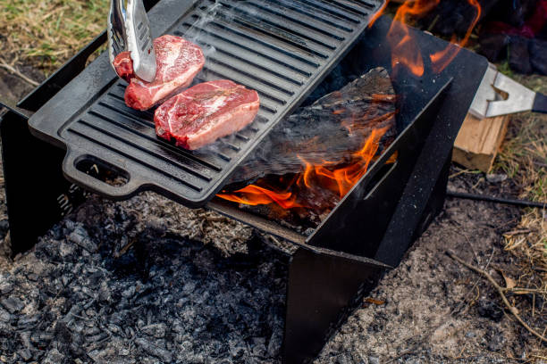 istock Beef steaks grilling on a cast iron plate on a camp fire. Campfire cooking. Outdoor BBQ. 1250673954