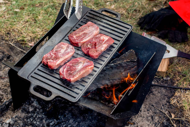 istock Beef steaks grilling on a cast iron plate on a camp fire. Campfire cooking. Outdoor BBQ. 1250674148