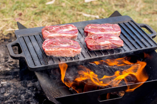 istock Beef steaks grilling on a cast iron plate on a camp fire. Campfire cooking. Outdoor BBQ. 1250674250