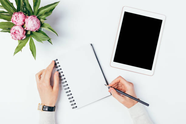 istock Female hands write in blank notebook near an electronic tablet 1250674787