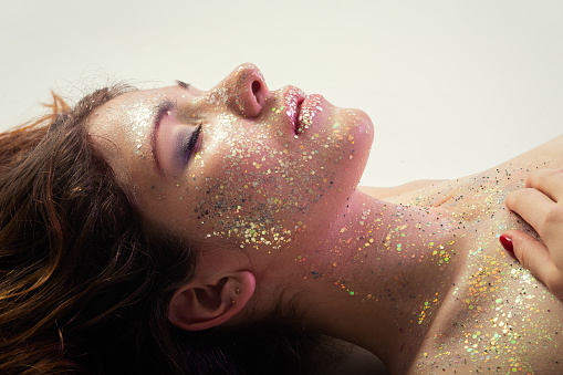 luxury young bare woman with shiny cosmetics lying with closed eyes