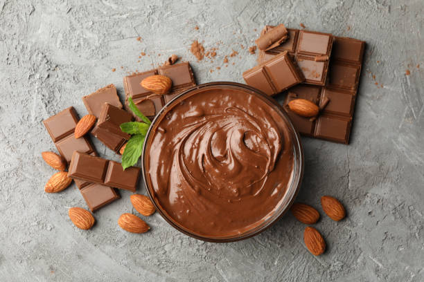 istock Bowl with chocolate and chocolate pieces on gray background 1250675766