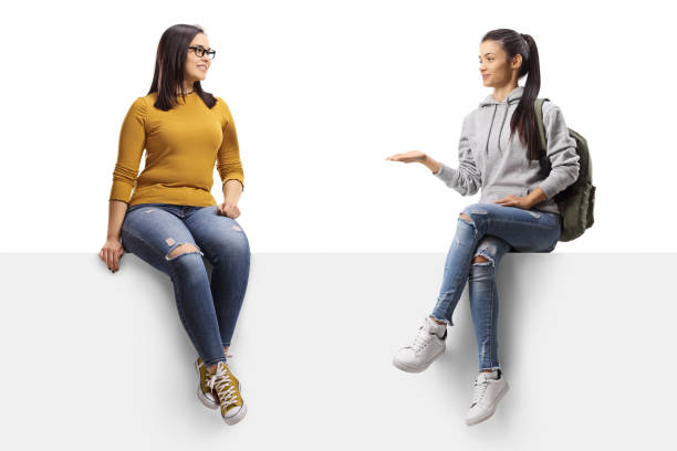 istock Two young female friends sitting on a panel and talking 1250678624