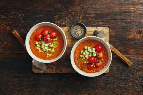 Authentic Gazpacho. Spanish Cold Tomato Soup. Flat lay top-down composition on dark wooden background. Horizontal image with copy space.