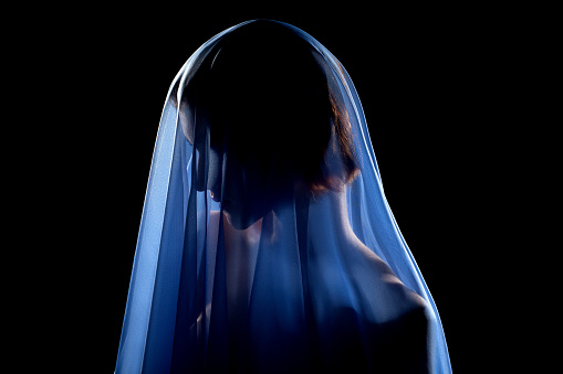 woman under blue veil posing sensually on black background, profile side view