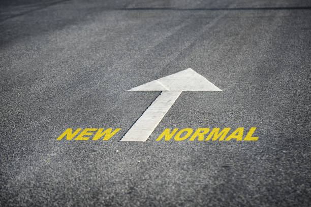 istock Words of new normal with white arrow marking on road surface 1250688664
