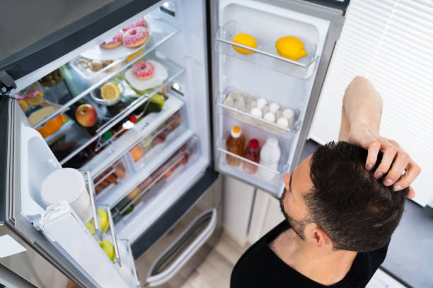 istock Hungry Confused Man Looking In Open Fridge 1250690724