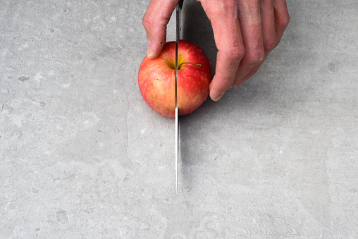 Cutting an apple fresh fruit preperation inside a kitchen on a chopping board