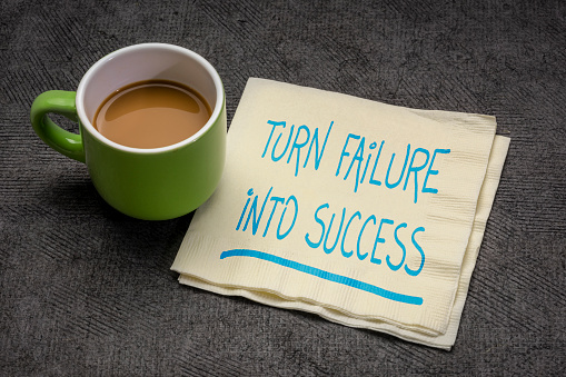 turn failure into success motivational note p handwriting on a napkin with a cup of coffee, business, career, education and personal development concept