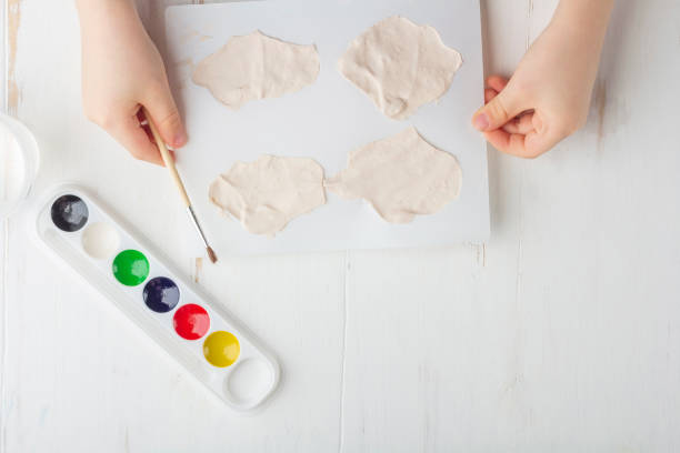 istock Step by step instruction: how to make plaster molding (figures). Concept of DIY and children's creativity. Making bas-reliefs on magnets. Step 7 kid hands hold plastic mold with ready-made plaster 1250701348