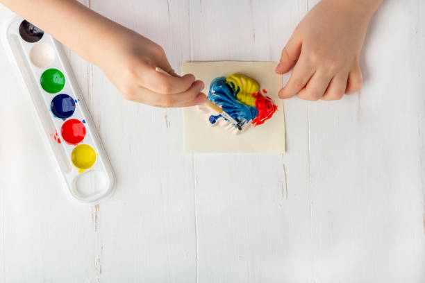 istock Step by step instruction: how to make plaster molding (figures). Concept of DIY and children's creativity. Making bas-reliefs on magnets. Step 7 coloring the finished fish figure with paints by kid 1250701352