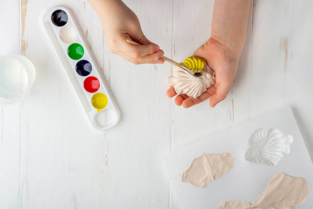 istock Step by step instruction: how to make plaster molding (figures). Concept of DIY and children's creativity. Making bas-reliefs on magnets. Step 7 coloring the finished fish figure with paints by kid 1250701356