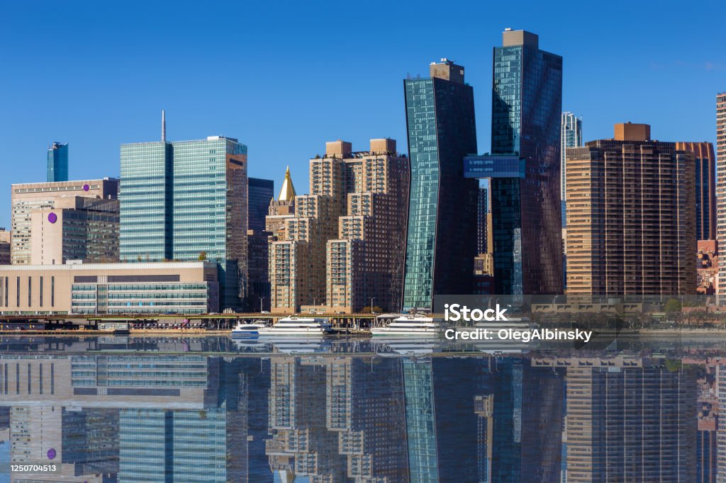 New York City Skyline with Skyscrapers of Manhattan East Side Reflected in East River, New York, USA Skyscrapers of Manhattan East Side and Water of East River lit by the morning sun, as seen from Gantry Plaza Park in Queens, New York, USA. Canon EOS 6D (full frame sensor) DSLR and Canon EF 24-105mm F/4L IS lens. New York University Stock Photo