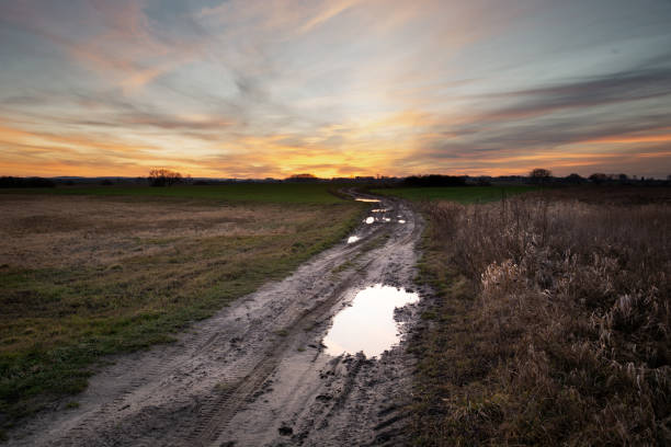 istock A puddle on a dirt road and sunset clouds 1250704753