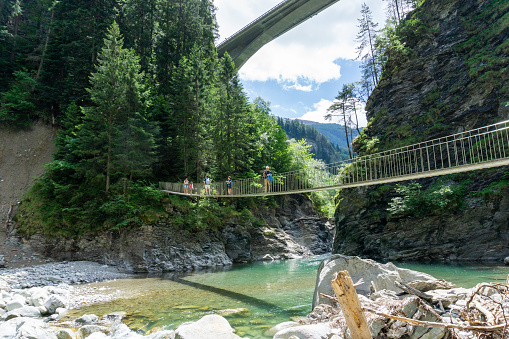 Rania, GR / Switzerland- 13 June 2020: Family hiking across a wooden suspension bridge over the Rhine River in the Viamala Gorge in the Swis Alps