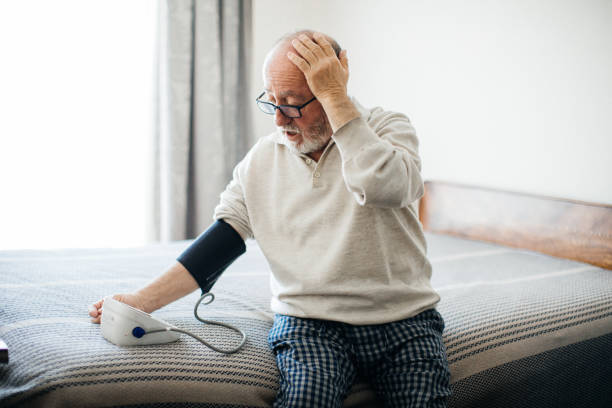 aktiv senior man som mäter blodtryck med blodtrycksmätare i sovrummet - blodtryck orolig bildbanksfoton och bilder