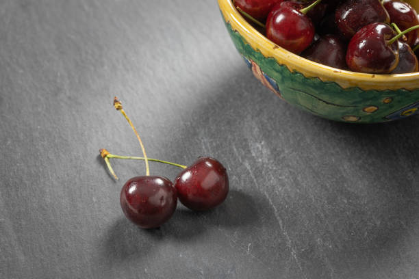 Bowl of cherries on a grey shale plate shot from above. Copy space