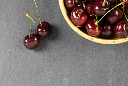 Bowl of cherries on a grey shale plate shot from above. Copy space